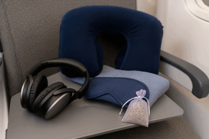 Kopfhörer, Schlafmaske, Lavendelsäckchen und Nackenkissen auf einem Flugzeugsitz oder Tisch.