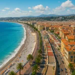 Panoramablick auf Nizza an der Côte d’Azur mit azurblauem Meer, Strandpromenade, Palmen und den typischen roten Dächern der Altstadt.