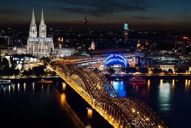 Beleuchteter Kölner Dom und Hohenzollernbrücke spiegeln sich im nächtlichen Rhein.