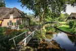 Malerisches Dorf Giethoorn in Holland mit reetgedeckten Häusern, kleinen Holzbrücken und idyllischem Kanal im Sonnenschein