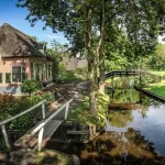 Malerisches Dorf Giethoorn in Holland mit reetgedeckten Häusern, kleinen Holzbrücken und idyllischem Kanal im Sonnenschein