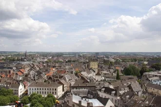 Panoramablick über Maastricht in den Niederlanden mit historischen Gebäuden, Kirchtürmen und der Maas im Hintergrund unter leicht bewölktem Himmel